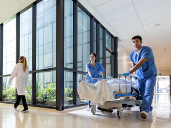 Two nurses moving a hospital bed down the hallway