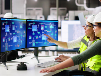 Two female technicians reviewing building automation designs on a computer screens