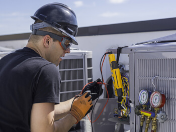 Technician wearing safety hat working on HVAC maintenance